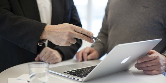 Deux hommes échangent devant un ordinateur portable